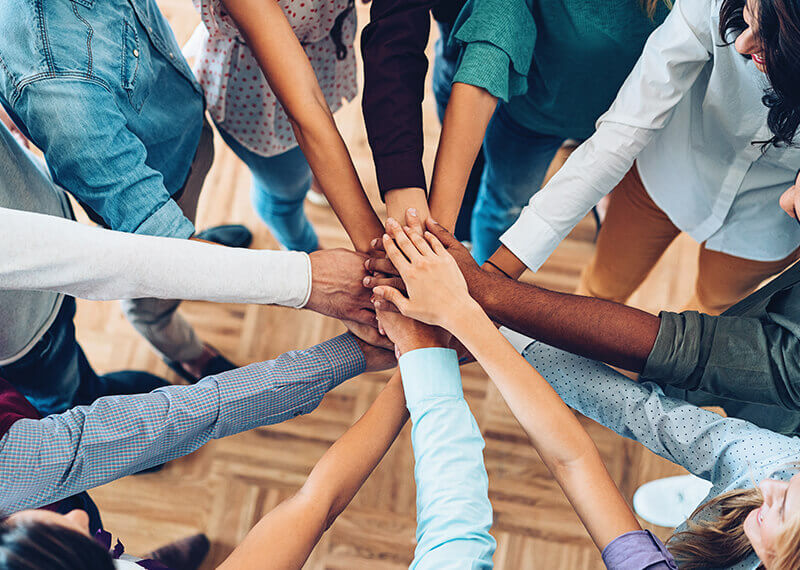 Men and Women of all races putting their hands in a circle on top of each other Men and Women of all races putting their hands in a circle on top of each other